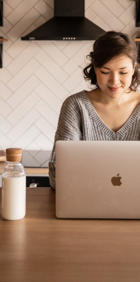 Women smiling while using macbook on kitchen counter